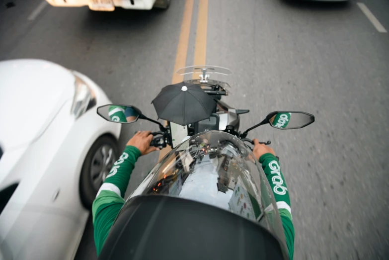 a person on a motorcycle holding up an umbrella