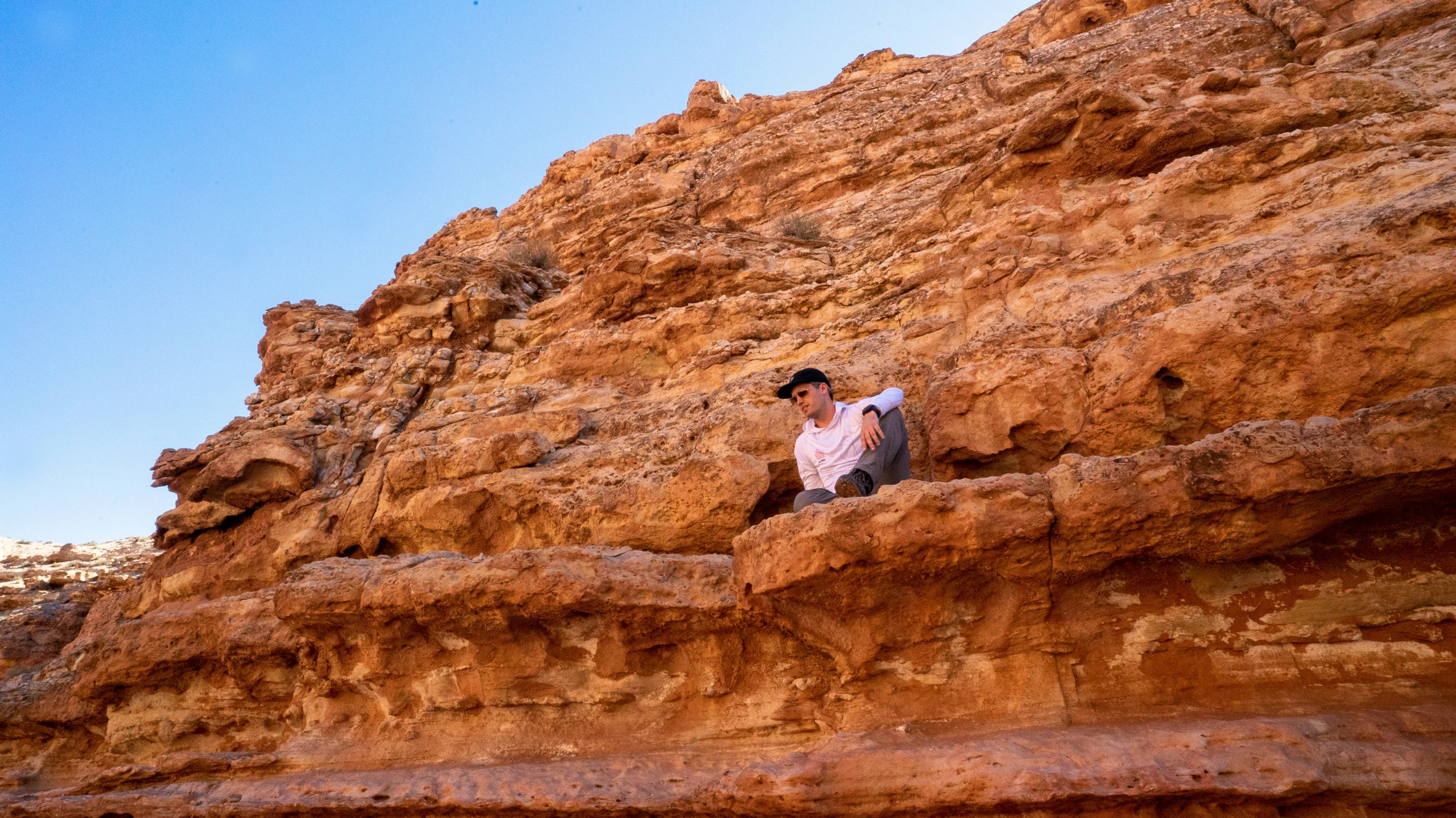 a person wearing black hat and shirt sitting on some rocks