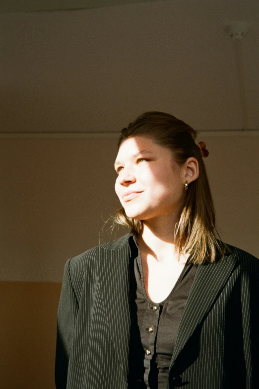 a woman in a blazer standing against a wall