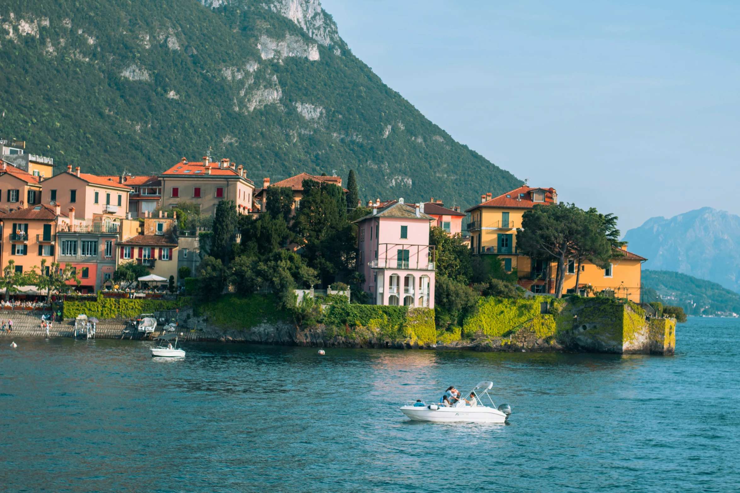 a small boat is out in the water in front of a town on a hill