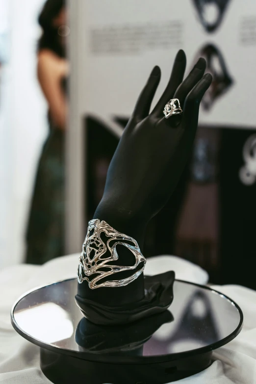 a womans hand in a black and white ring sits on top of a plate