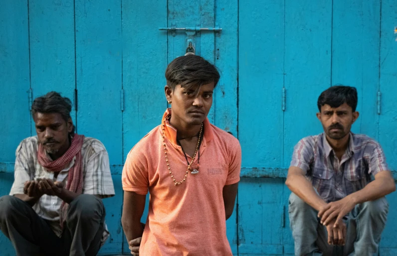 three men standing outside with one man staring