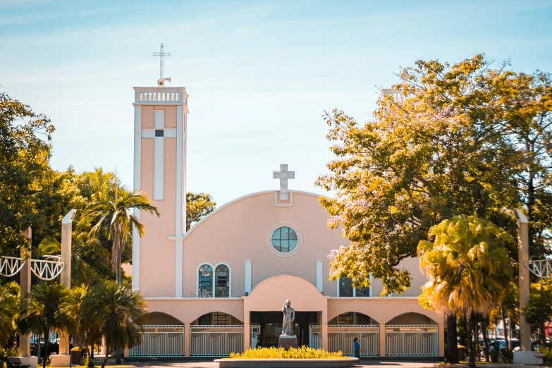 the church has trees on both sides of it and a cross in the middle of it