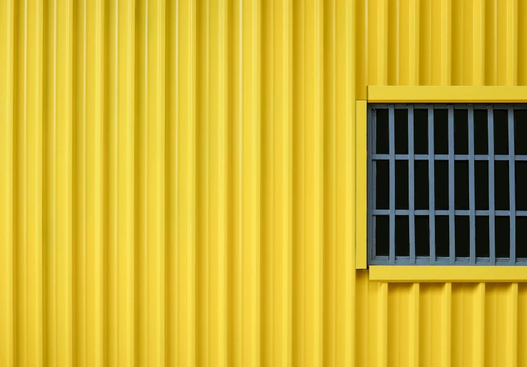 the yellow wall with a window has bars on the side