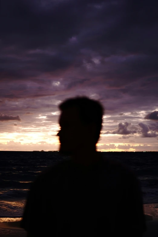 a silhouetted person is standing on the beach by an ocean