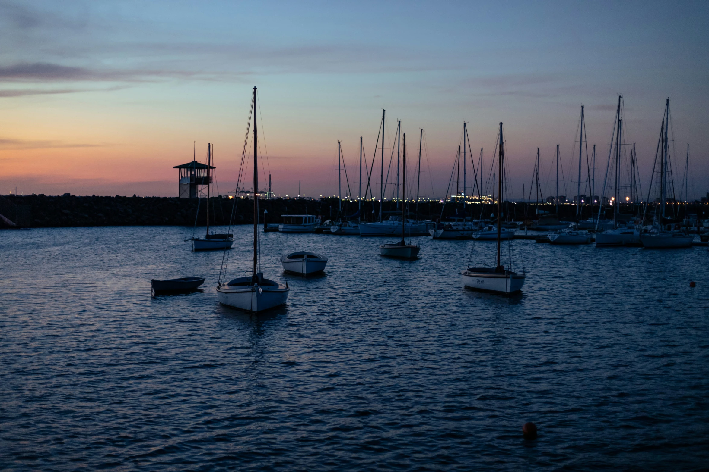 a sunset in a harbor of several boats