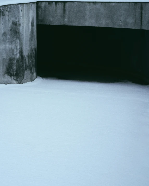 someone walking past a concrete structure in the snow