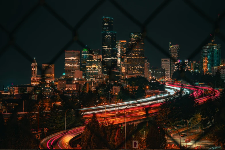 an aerial s of a street at night with city lights behind a chain link fence