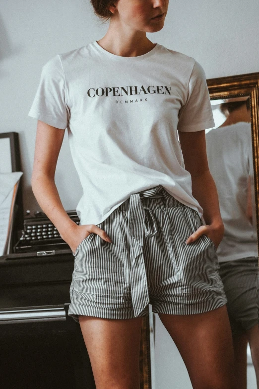 a woman standing in front of a mirror wearing shorts and t - shirt