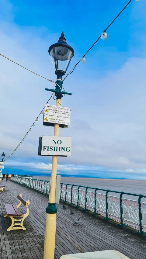 a sign is hanging off the post by the water