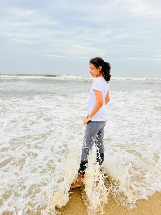 an asian woman is standing in the waves at the beach