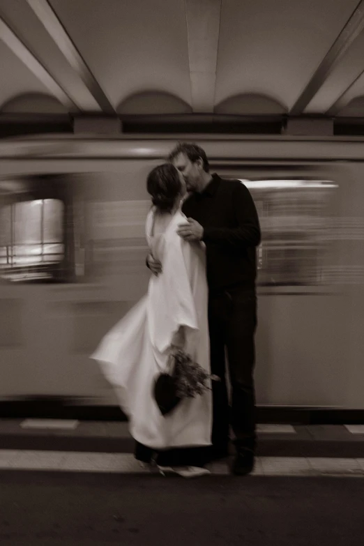 a man and woman are kissing near the train station