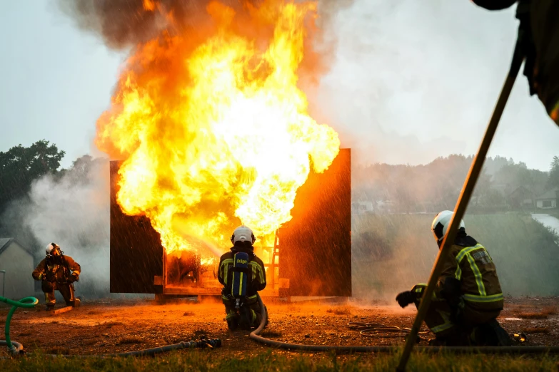 four fire fighters are working in front of a burning building