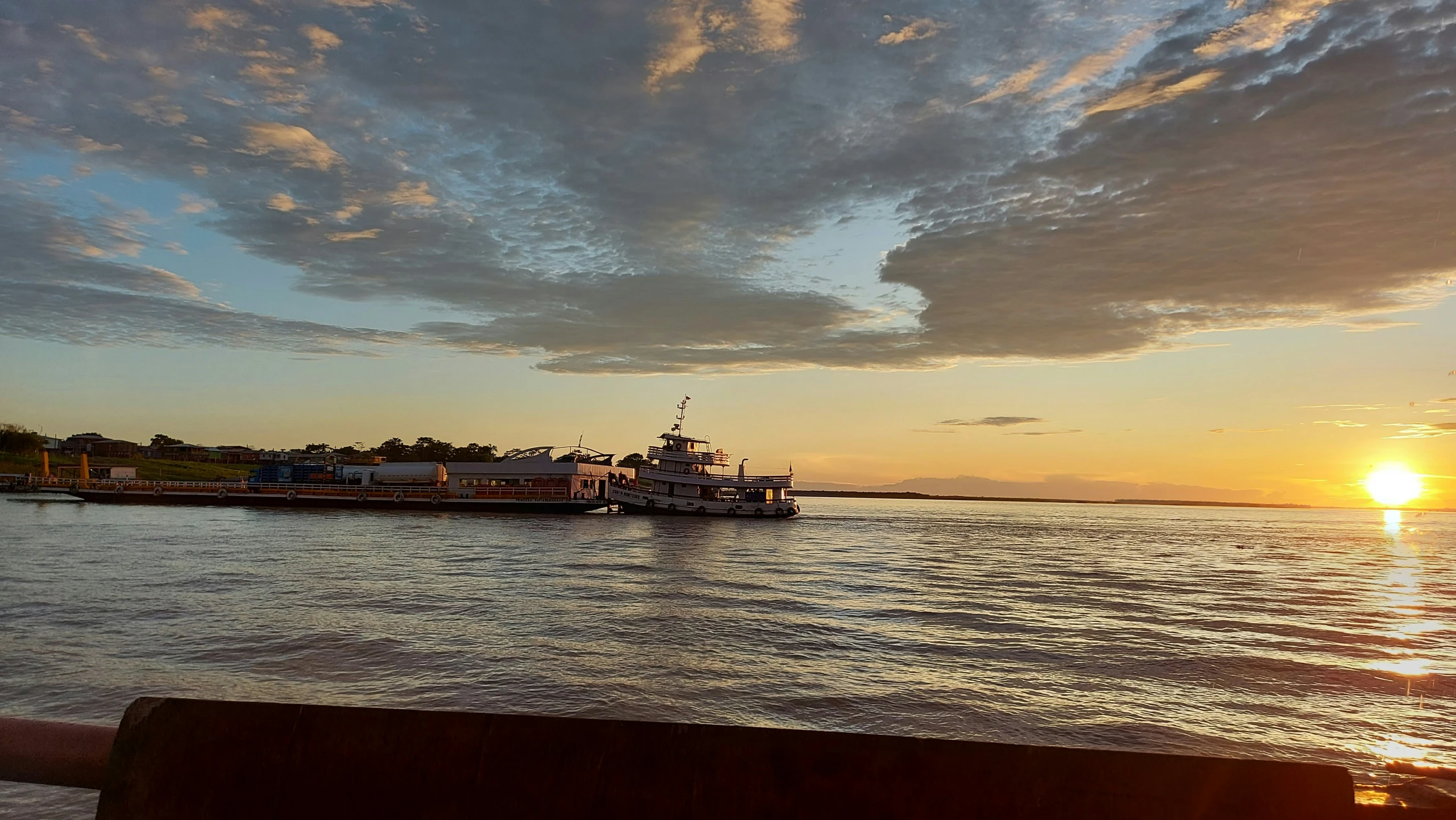 a barge floating in a large body of water at sunset