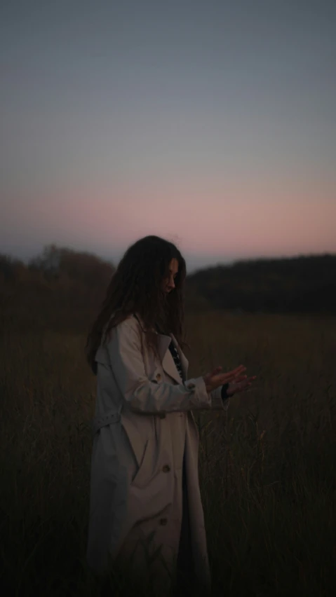 a woman is standing in tall grass and touching the ground