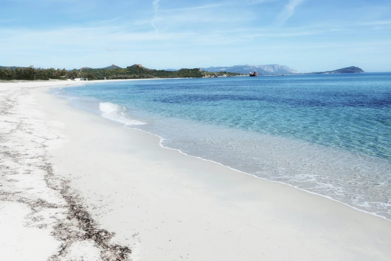 a sandy beach next to the ocean and another body of water