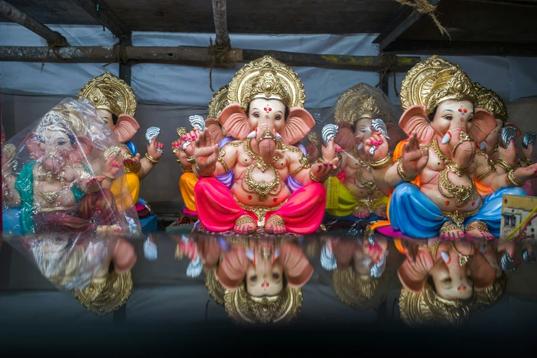 four ganpatis and two on a mirror reflecting surface