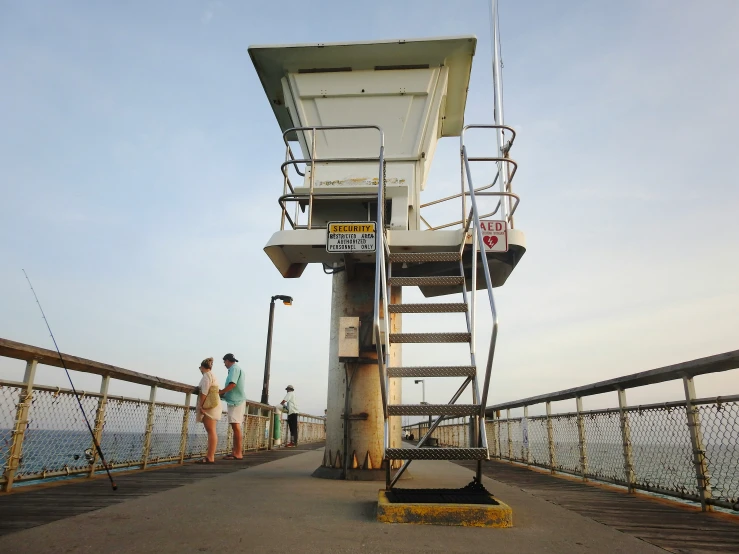 two people standing at the end of a bridge with a cell phone