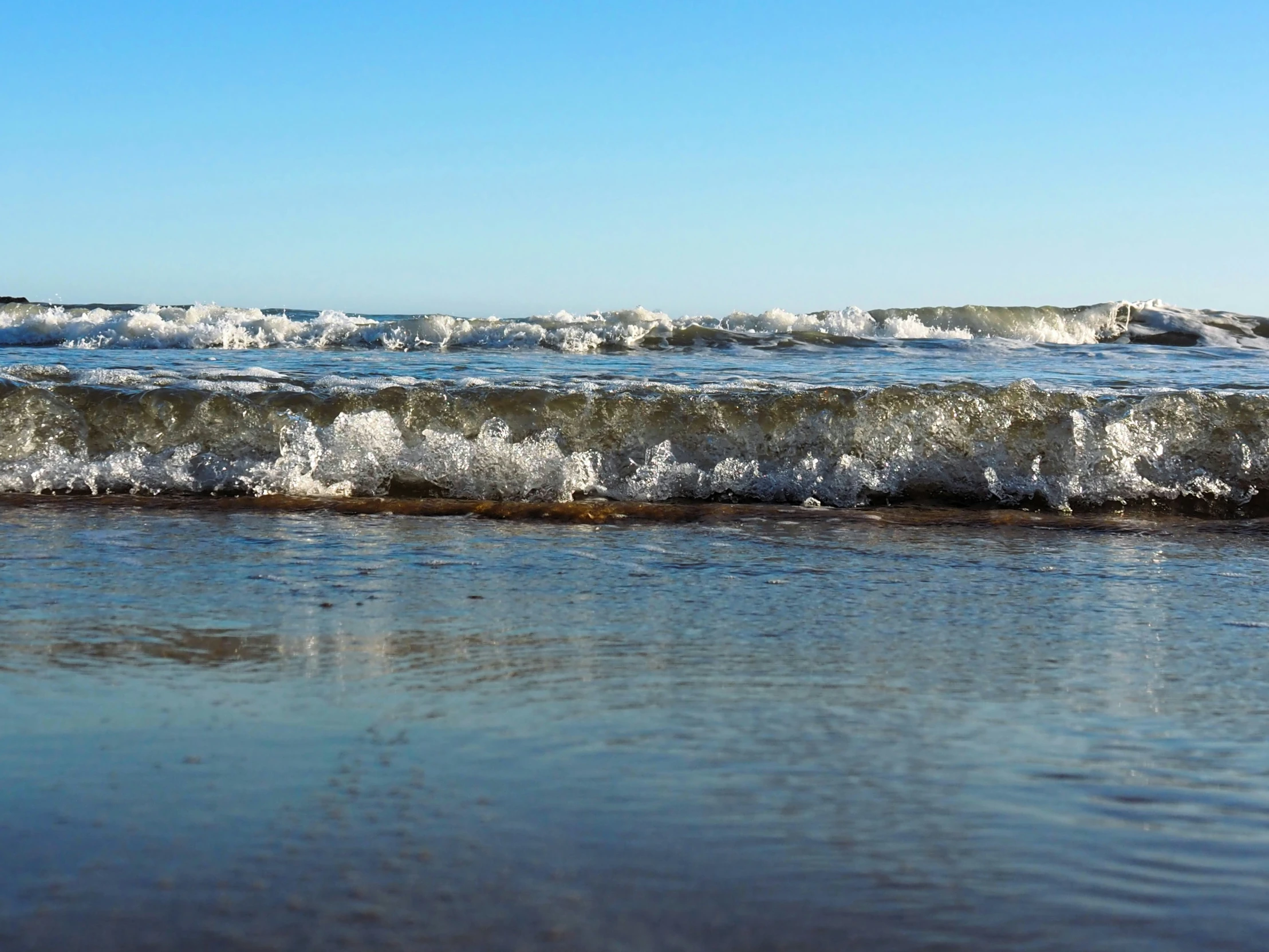 water on the shore, with waves crashing into the sand