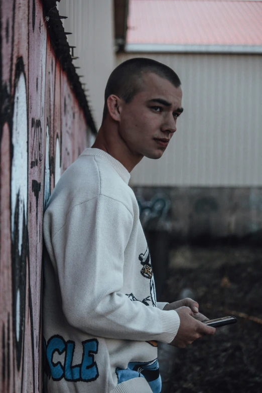 young man in sweatshirt holding tablet next to building