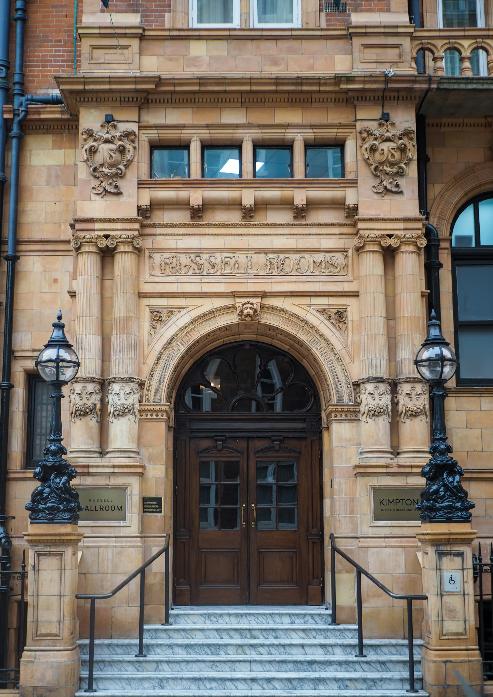 a front entrance of an old building with stairs and a clock