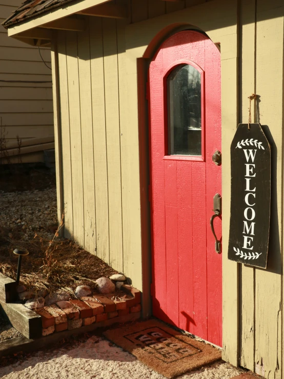 a welcome sign in front of a red door