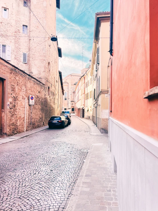 a cobblestone street with a car parked on the right