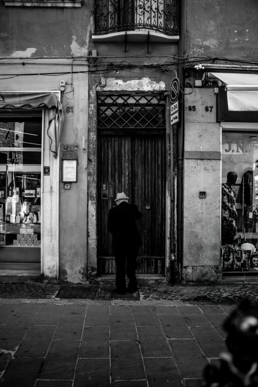 black and white pograph of a person standing in front of a building