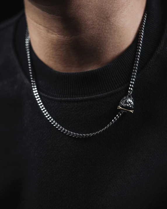 a man wearing a black t - shirt and a chain with heart charms