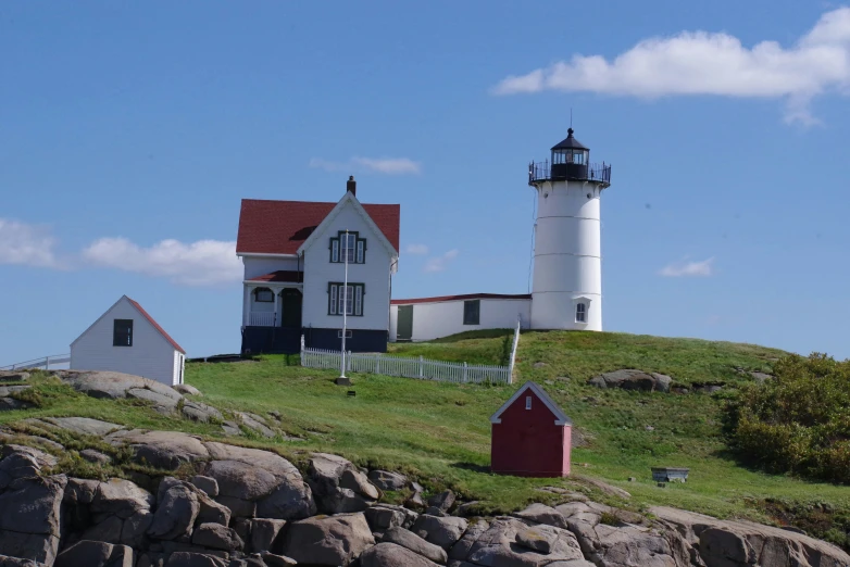 a white house on top of a grassy hill next to a light house