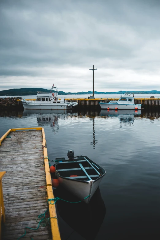 small boat docked at dock next to fence with boats in background