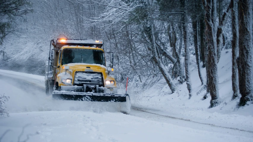 a snow plow on the side of a road in a snowy area