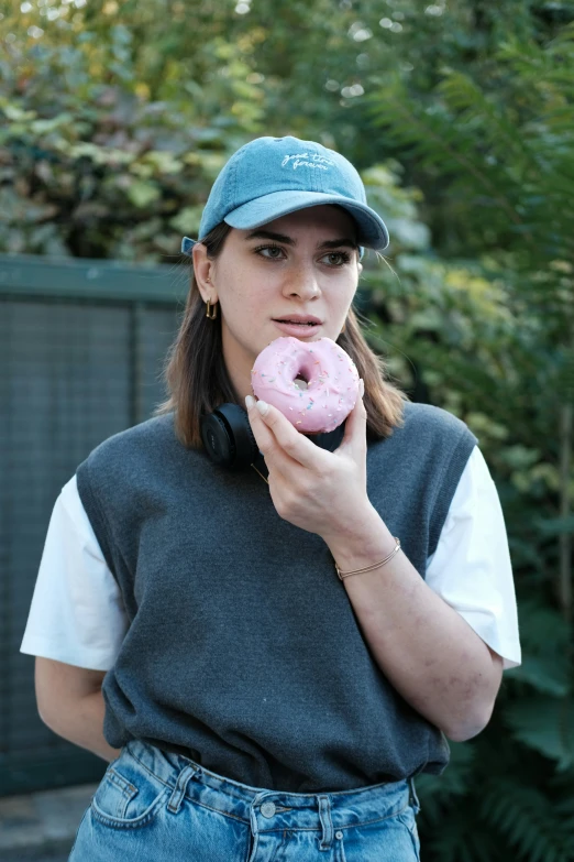 a girl wearing headphones and holding a pink doughnut in her hand