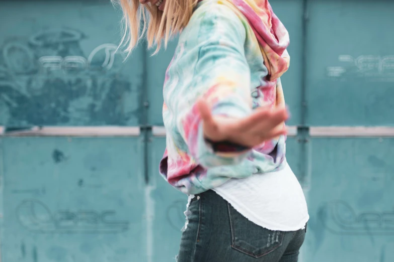 a woman wearing a tie dyed shirt carrying an object