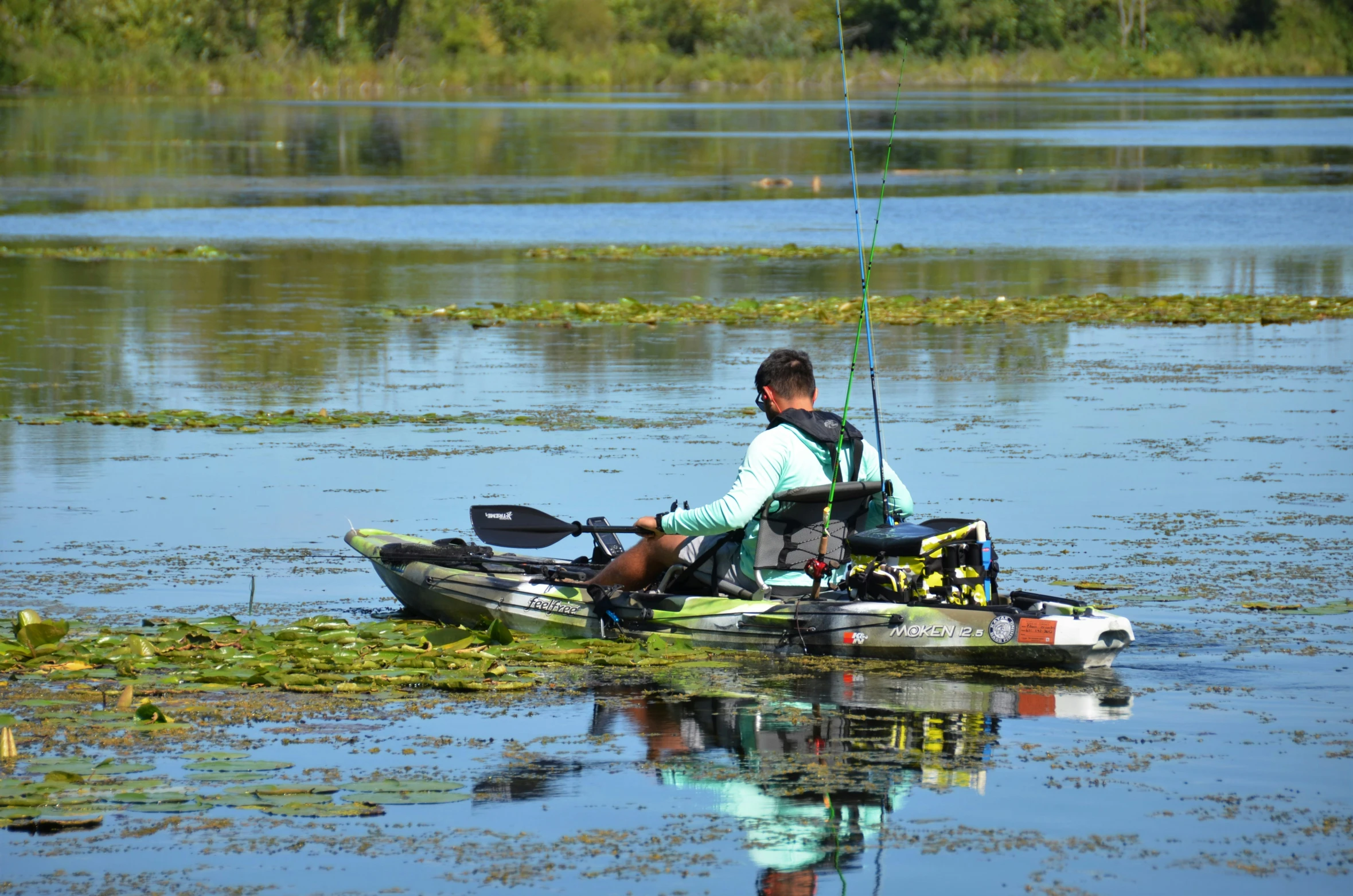 a man in the water with a fishing pole in his kayak