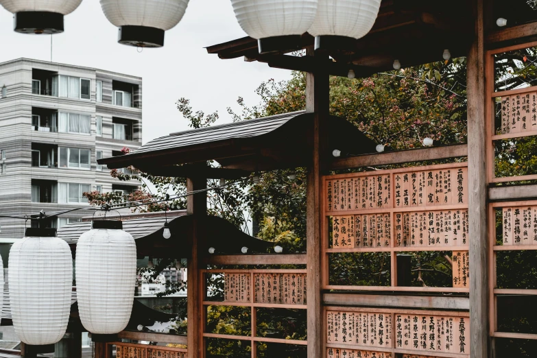 lantern lights hang from a pergoline in front of some tall buildings