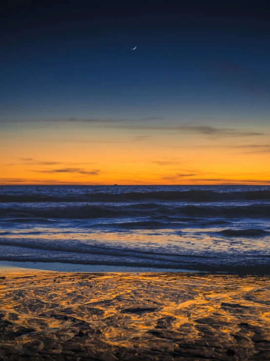 an orange and blue sky with the sun rising over the ocean