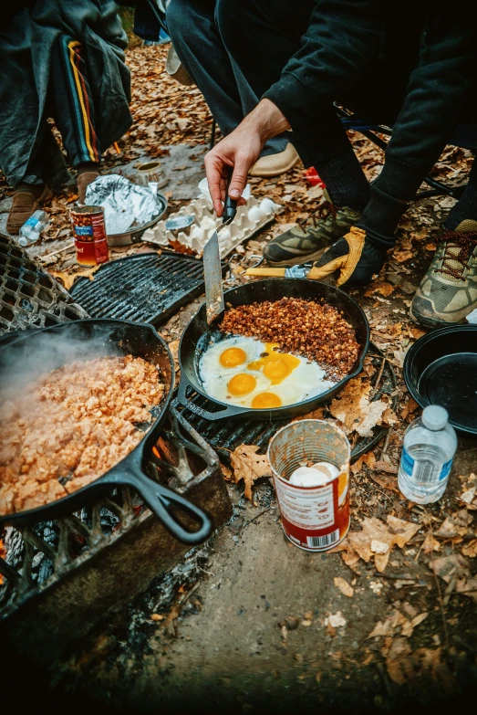 a man is standing over a bbq and holding two eggs