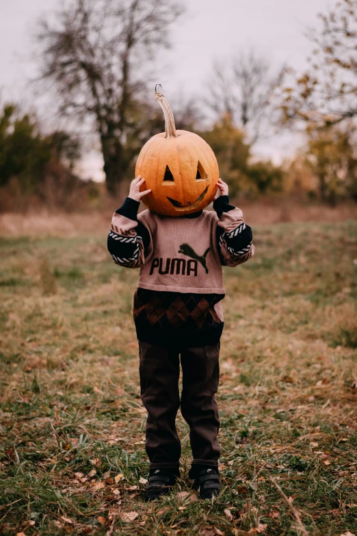a young child holding up a pumpkin to his face