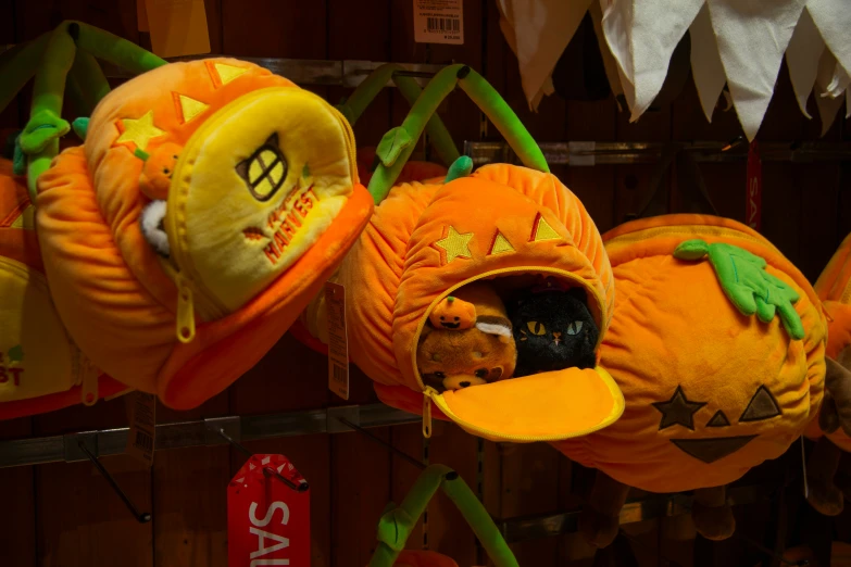 three plush pumpkin hats for sale on a market