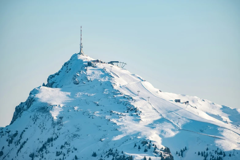 the top of a snow covered mountain in front of a blue sky