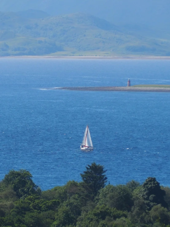 there is a sailboat on the water with mountains in the background