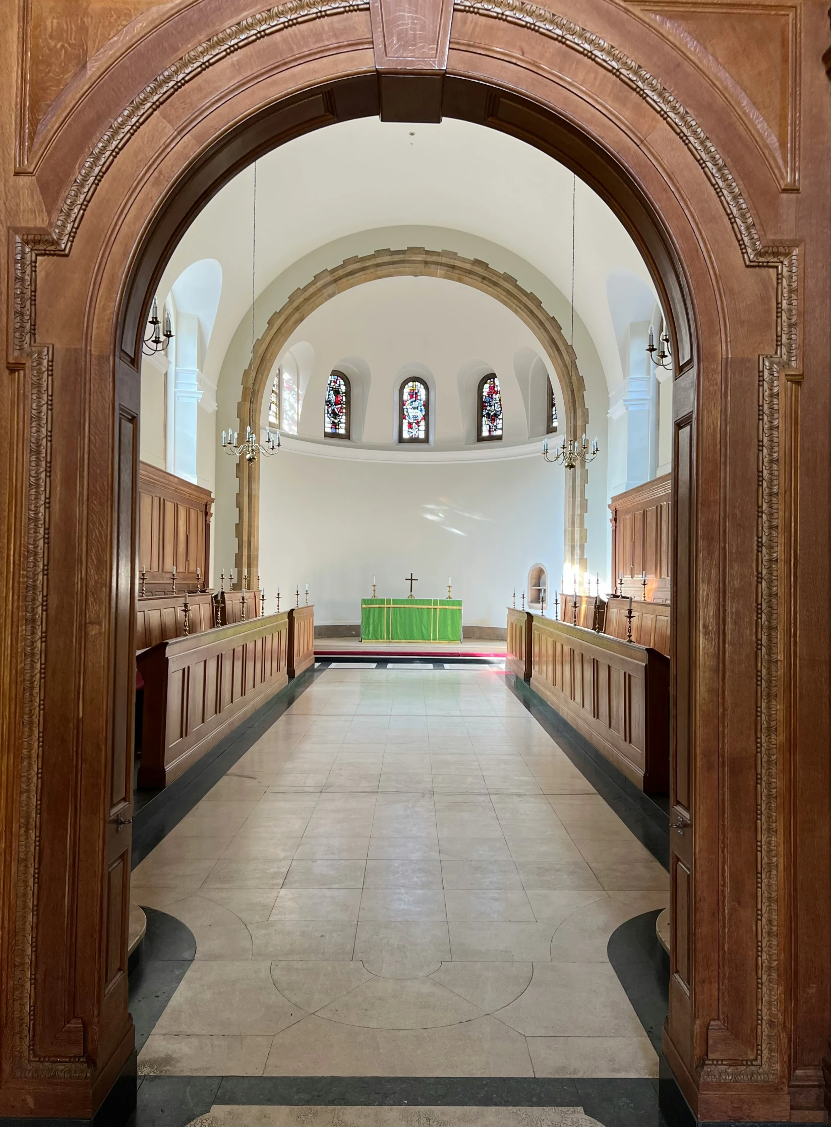 a church entrance with wooden pews lined along the wall and green pews sitting in the background