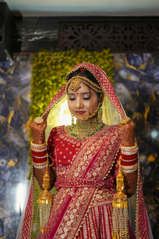 a bride wearing a maroon and gold sari and headpiece