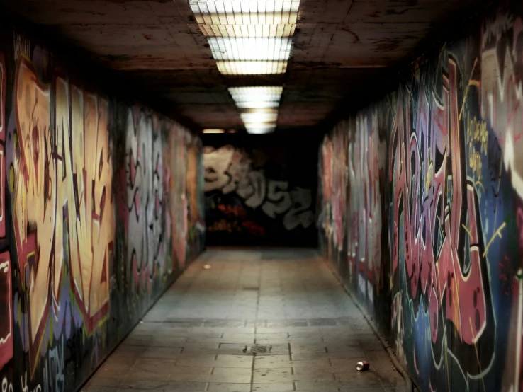 a graffiti covered tunnel under a roof next to a light