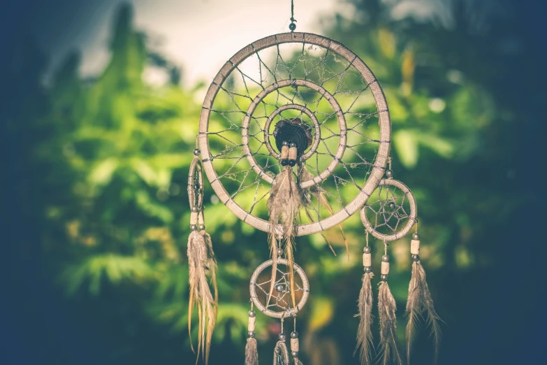 a circular decorative, wooden hanging mobile with feathers