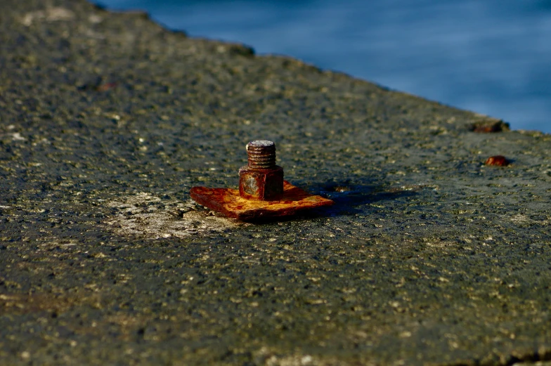 a piece of orange rusted metal sitting on top of the cement