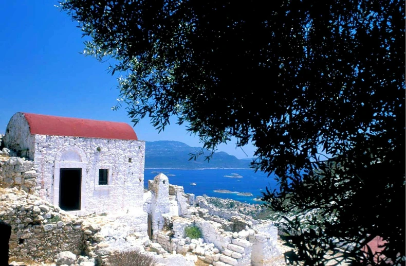 a small building that is sitting on some rocks by the water