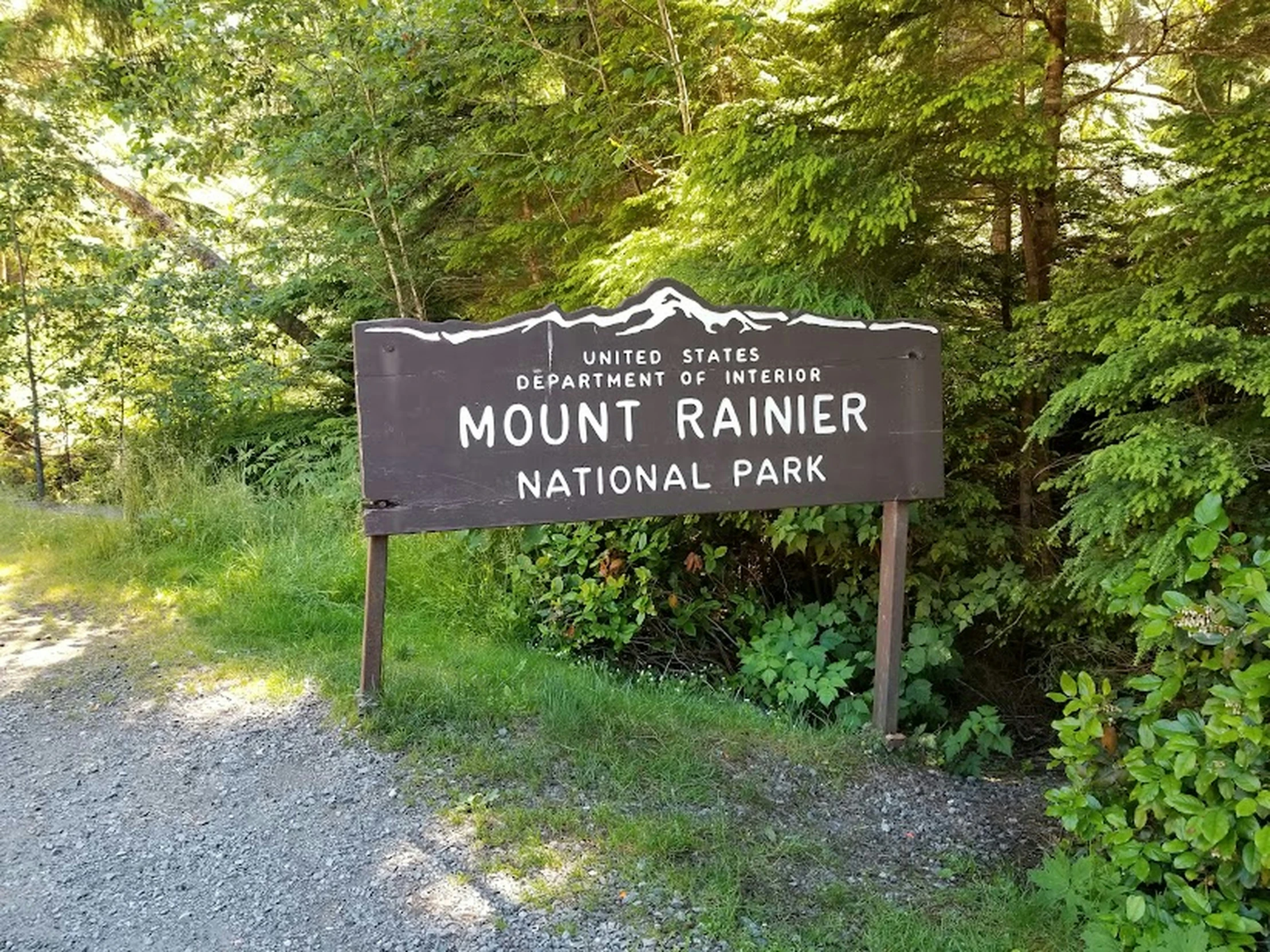 a sign on the side of the road showing that the mount rainier national park is open