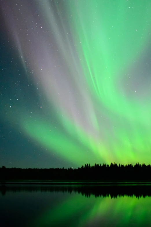 the aurora or northern lights are reflected in the water